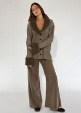 Saco marrón con rayas verticales en tonos beige, con cuello y puños de tejido rizado. Cierre frontal con botones.