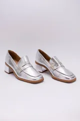 Mocasín clásico plateado, todo en cuero, con taco cuadrado y suela marrón.