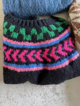 Sweater de punto tejido a mano en mohair, con diseño de canesú estampado en tonos azul, rojo, blanco y turquesa. Presenta cuello redondo y mangas largas.