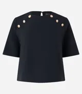 Blusa negra de crepé con cuello redondo, mangas cortas y botones dorados decorativos en los hombros.