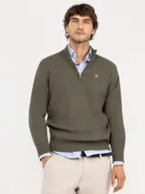 Sweater de punto en color verde oliva, con diseño de medio cierre frontal y cuello alto. Presenta puños y ruedo acanalados, con un pequeño logo bordado en el pecho.