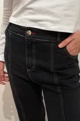 Jean oxford de tiro medio en color negro, con costuras a la vista y corte acampanado en la parte inferior.