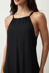 Vestido midi de color negro con escote halter y breteles finos. Presenta un corte holgado y fluido con caída suave.