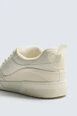 Zapatilla deportiva estilo basket con cordones gruesos, confeccionada en una combinación de piezas en tonos crema y beige, con suela de goma con volumen.