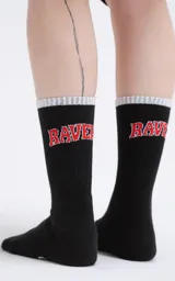 Medias 3/4 de algodón color negro, con el texto 'RAVERS' bordado en rojo en la parte superior y logo 'LUXO' en la planta del pie. Presentan un borde superior acanalado en color gris claro.