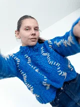 Sweater tejido a mano con lana merino color negro y bordado con lana color crudo. Es corto, a la cintura y de cuello alto.