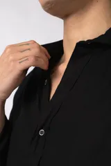 Camisa de manga larga con cuello clásico y cierre frontal de botones. Presenta un calce relajado y una textura liviana.