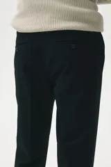 Pantalón de vestir negro, corte slim fit, con cierre y botón frontal, bolsillos laterales y bolsillos insertados traseros con botón. Presenta raya marcada en las piernas.