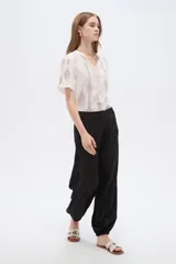 Pantalón de poliéster color negro, de tiro alto y corte holgado con frunces en los tobillos.