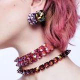Gargantilla con cristales tridimensionales de talla piramidal en tonos violetas, con montura con baño dorado y engaste abierto. Cierre de seguridad. Forma parte de la familia Chroma.