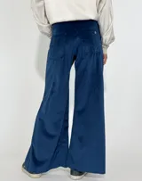 Pantalón de terciopelo gris, de corte palazzo, con bolsillos laterales y cierre frontal con botón y cremallera.