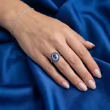 Anillo de plata 925 con diseño ovalado, presenta una piedra central en color zafiro rodeada por un doble halo de circonias blancas y azules.