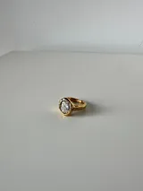 Anillo de acero quirúrgico con baño de oro y piedra central transparente de corte ovalado.
