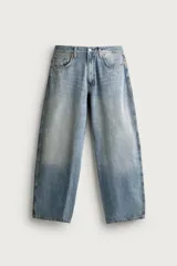 Jeans balloon fit de corte relajado y tiro medio, confeccionados en denim de algodón con efecto lavado. Presentan diseño de cinco bolsillos y cierre frontal con cremallera y botón metálico.