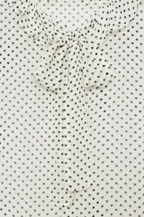 Blusa de viscosa con estampado de lunares, cuello redondo con escote en pico, volantes y lazada frontal. Presenta manga corta y bajo recto.