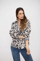 Camisa de manga larga con cuello clásico y cierre frontal de botones. Presenta un estampado de manchas tipo animal print en tonos blanco y negro.