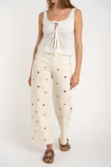 Jean de corte recto y tiro medio, color off-white, con diseño de pequeños bordados en forma de cruz distribuidos por toda la prenda.