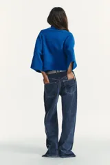 Jersey de punto liso en color azul vibrante, con cuello subido y mangas anchas de diseño acampanado. Presenta acabados en rib en el cuello y los puños.