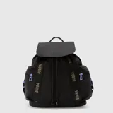 Mochila Bubba modelo Mila, color negro con detalles en lila. Confeccionada en nylon, cuenta con solapa superior, cierre de cordón ajustable, bolsillos laterales con cierre y correas decorativas con el logo de la marca.