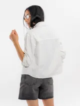 Campera de jean blanca con bolsillos frontales con solapa y botones metálicos oscuros.