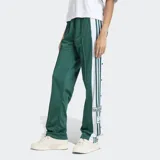 Pantalón deportivo Adidas Adibreak de corte holgado, color verde con franjas laterales blancas y las icónicas tres rayas en verde. Presenta botones a presión a lo largo de los laterales y logo de la marca en la parte inferior.