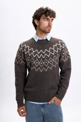 Buzo de tejido de punto con diseño jacquard en el pecho, cuello redondo y mangas largas. Presenta un patrón geométrico en tonos claros sobre una base de color marrón.