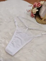 Tanga de diseño strappy confeccionada en lycra blanca con detalles de encaje en la parte superior frontal. Presenta tiras regulables en la cintura y laterales para un ajuste personalizado.