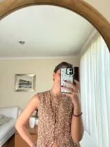 Chaleco de lino estampado con diseño ikat en tonos marrón y crudo, sin mangas, con cuello redondo y cierre frontal de botones tapados.
