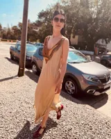 Vestido midi de satén en tono dorado verdoso, con escote en V profundo decorado con un mix de cueros unidos artesanalmente. Presenta tajos laterales, espalda descubierta y un diseño fluido con gran movimiento.