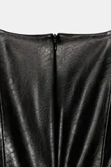 Top sin mangas de cuello barco, confeccionado en tejido con efecto piel. Presenta un diseño entallado con costuras verticales y un cinturón fino integrado en la cintura con hebilla metálica. Cierre posterior con cremallera oculta.