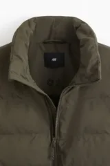 Chaleco acolchado color verde militar, con cuello alto, cierre frontal y bolsillos laterales con cierre.