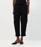 Pantalón de sastrería corte carrot, color negro con rayas verticales blancas. Presenta pinzas frontales, cintura con pasantes y bajo ajustado.