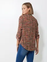 Blusa de gasa con estampado geométrico en tonos tierra (marrón, rojo, verde, amarillo). Presenta cuello solapa con escote en V y mangas largas ajustables con presilla y botón.