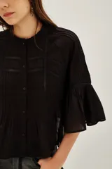 Camisa de algodón color negro, con cuello redondo, mangas tres cuartos abullonadas y detalles de encaje y alforzas en el frente y mangas.