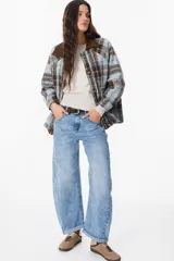 Chaqueta de corte holgado con estampado de cuadros en tonos beige, marrón y amarillo. Presenta cuello camisero en pana marrón, cierre frontal con botones y mangas largas con puños abotonados.