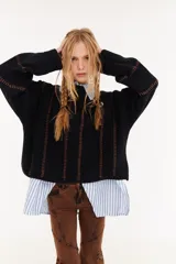 Sweater de punto color beige, con diseño de textura acanalada en mangas y espalda, cuello polo en color bordó y parche decorativo en la parte superior de la espalda.