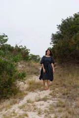 Vestido túnica midi de corte recto, color azul marino con rayas verticales blancas, mangas cortas abullonadas y lazo ajustable en la cintura.