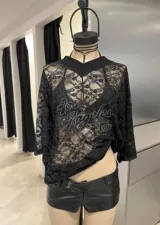 Remerón de encaje negro con diseño de cuello en V y mangas cortas. Presenta un estampado frontal bordado con texto y el número 32.