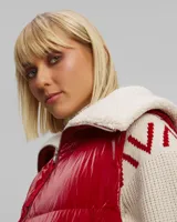 Chaleco puffer rojo con cuello de sherpa color crema, cierre frontal con cremallera y bolsillos laterales.