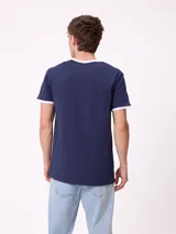 Remera de corte regular fit, color azul marino con cuello y bordes de mangas en color blanco. Presenta el logo de la marca Rusty estampado en el centro del pecho.