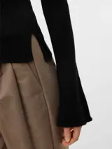 Top de punto acanalado color negro, con cuello bote y mangas largas de corte recto. Confeccionado en una mezcla de viscosa y poliéster, presenta una textura suave y ligera.