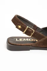 Chatita tipo slingback de gamuza color marrón, con punta fina y cierre de hebilla metálica ajustable en el talón.