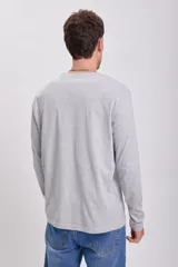 Remera manga larga gris claro, de corte recto y cuello redondo.