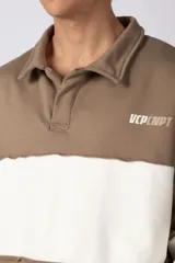 Buzo tipo polo de calce relajado con diseño de bloques de color en tonos marrón y blanco. Presenta cuello polo, cierre frontal parcial y logo estampado en el pecho. Confeccionado en tejido pesado con estructura.