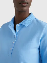 Chomba celeste de piqué de algodón con cuello ribeteado, cartera de cinco botones, logo de Tommy Hilfiger bordado en el pecho y bandera de Tommy Hilfiger bordada en la manga.