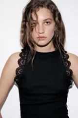 Top negro de punto rib con cuello halter, sin mangas y detalles de encaje a tono en las sisas.