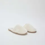 Pantuflas abiertas de pelo sintético color beige con suela marrón.