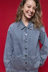Sobrecamisa de jean de calce relajado color gris, con solapa clásica, bolsillos frontales y cierre de botones metálicos.
