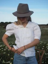 Blusa blanca de lino, de manga corta, con cuello marinero amplio decorado con estampado azul.