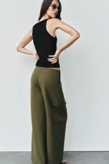 Pantalón cargo de tiro medio, color verde militar, con corte recto y bolsillos laterales de plastrón con solapa. Presenta detalles de nervios frontales y cierre con cremallera y gancho metálico.
